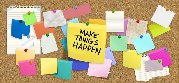 Image of a cork noticeboard with various coloured notes pinned to it, including centrally a yellow note with black MAKE THINGS HAPPEN text