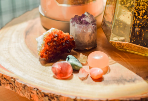An array of crstals, in differing sizes with a lit candle in the background