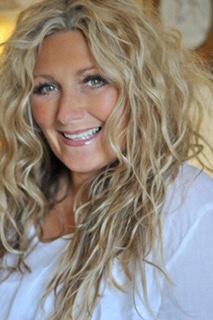 Colour photo of Amanda Prowse. She has long curly blonde hair and is smiling at the camera. 