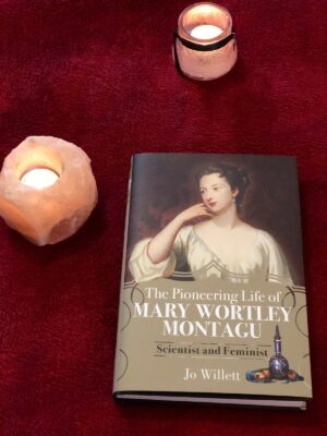 Image of the book against a red background, with candles nearby