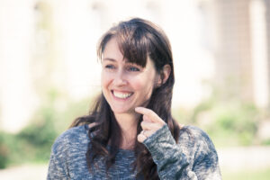 Photo of Juliet, who has shoulder length brunette hair with achoppy fringe and is smiling broadly