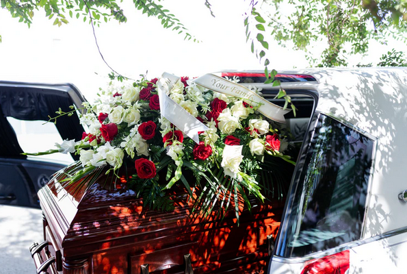 Image of a flower covered coffin in the back of a hearse