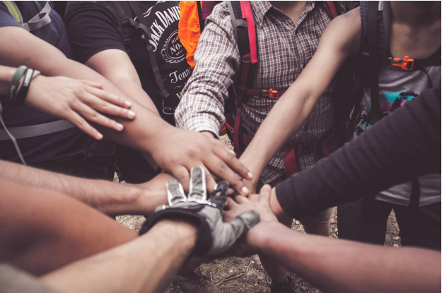 Image of a circle of people, hands and arms visible, with hands in a centre stack